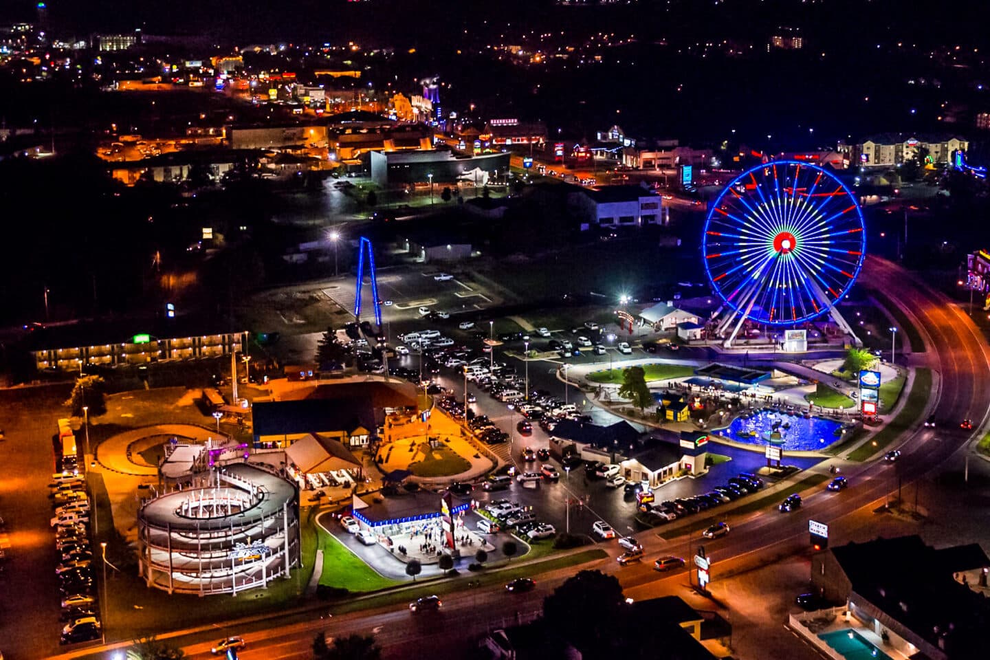Aerial nighttime view of the Branson Strip with Ferris wheel and attractions lit up
